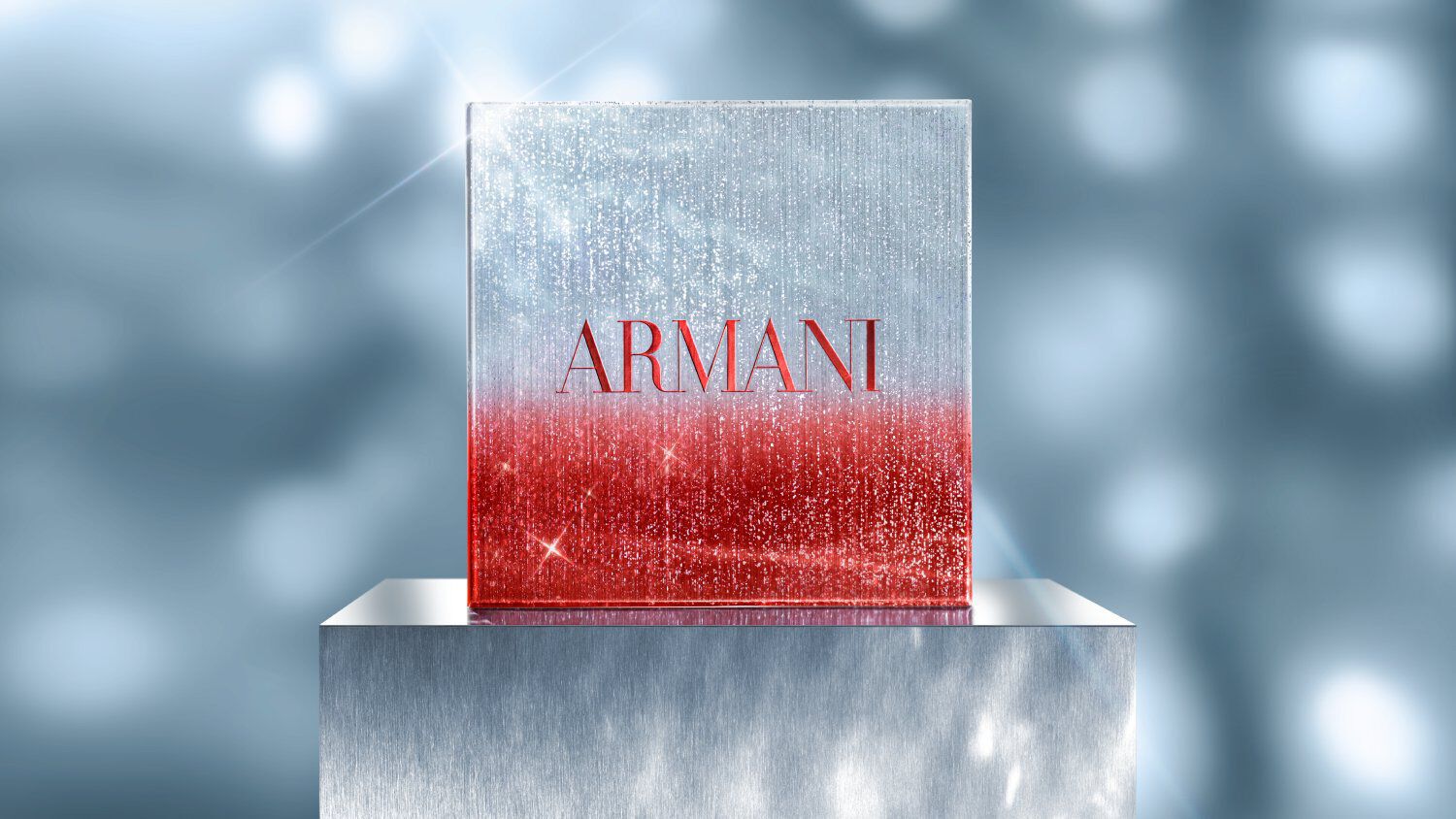 Square Armani holiday gift box in red and silver glitter gradient, displayed on a metallic pedestal with a sparkling, festive blue background.