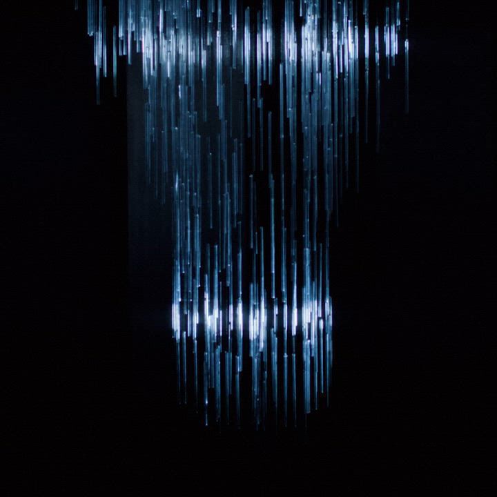 A mesmerizing video featuring a glamorous woman with striking silver eyeshadow and dark red lips, adorned with long blue sparkly earrings. She holds a Giorgio Armani perfume bottle, set against a backdrop of shimmering lights. The video showcases elegance and allure.