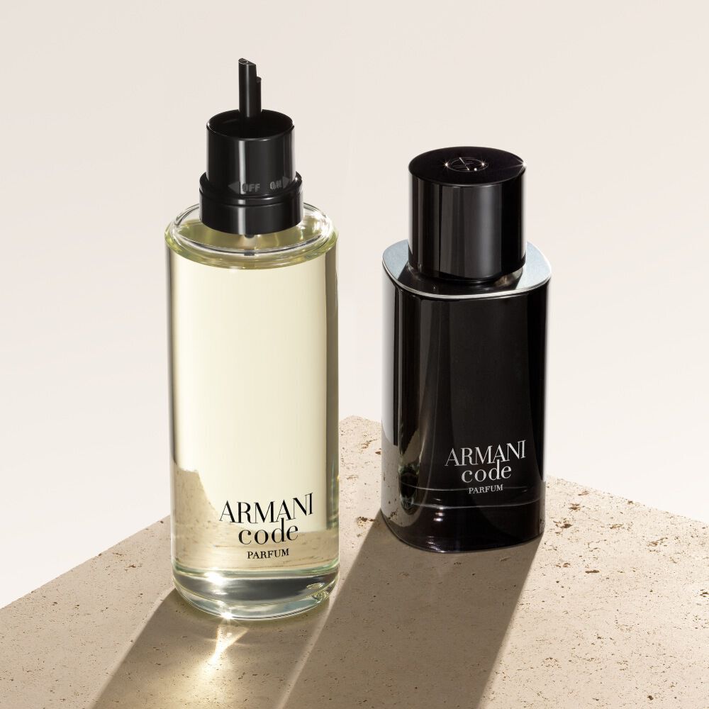 Deux flacons d'Armani Code Parfum sont presentes sur un fond texture beige. Le flacon de gauche est une recharge, plus claire et transparente, tandis que celui de droite est le flacon noir opaque classique du parfum.