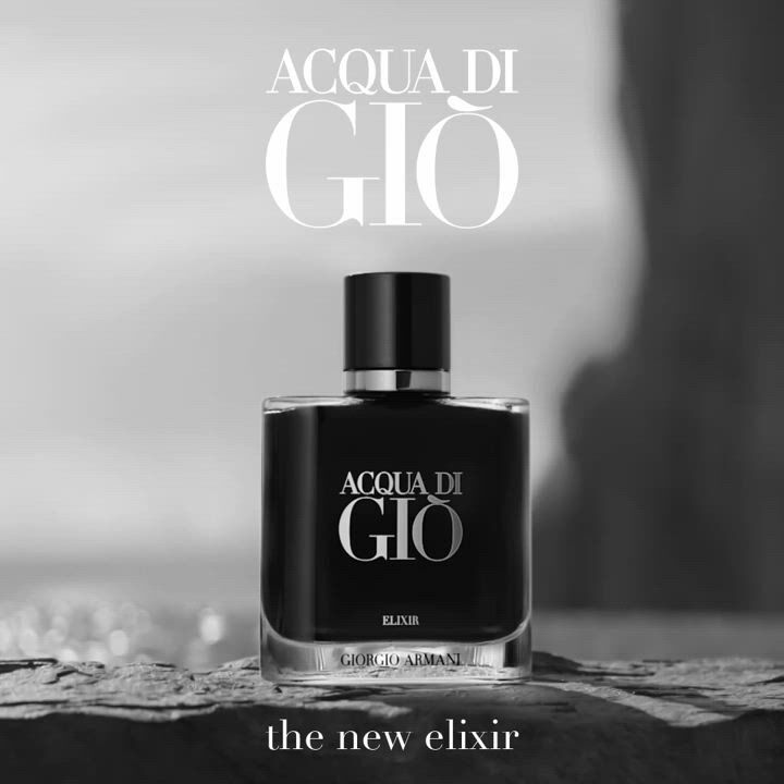 A sleek black bottle of Acqua di Gio Elixir by Giorgio Armani, set against a blurred coastal background.