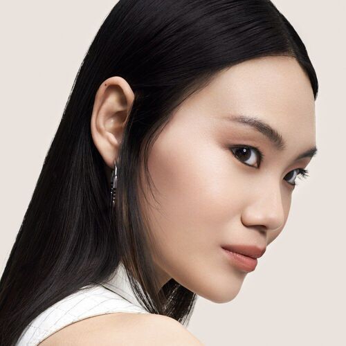 Portrait d'une femme asiatique aux cheveux longs et lisses, regardant legerement de profil, avec un fond neutre.