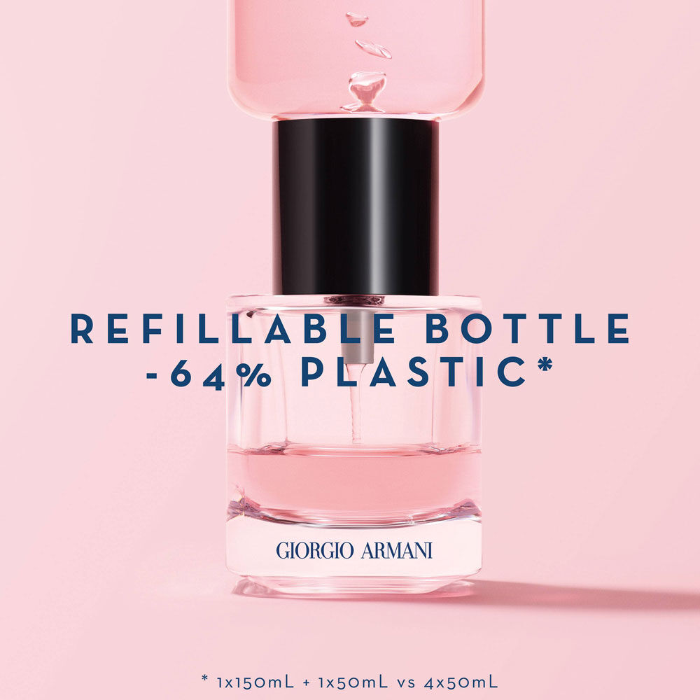 A Giorgio Armani refillable perfume bottle with a pink liquid inside, featuring a sleek design and a black cap. The text highlights "-64% plastic" and details about the bottle's refillable capacity.