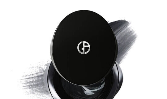 Zwart makeupproduct met een glanzend deksel en een logo op een grijze achtergrond.
