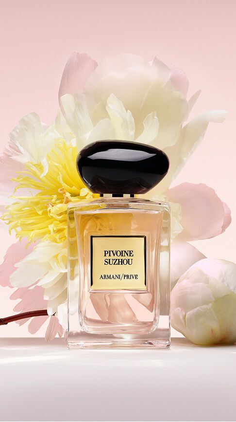 Armani/Prive Pivoine Suzhou : un flacon revelant un jus rose tendre, niche parmi des pivoines blanches et jaunes luxuriantes, celebrant la grace et l'eclat radieux de la nature.