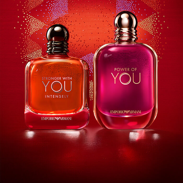 Twee Emporio Armani-geuren, Stronger With You Intensely en Power of You, tegen een feestelijke rode achtergrond.​
