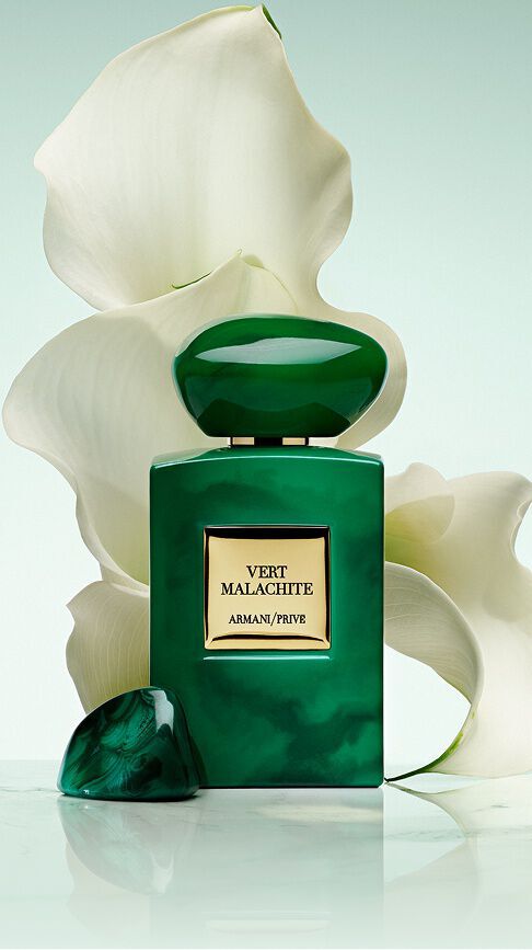 Armani/Prive Vert Malachite: a vibrant emerald green bottle with a stone-like cap, rising before pristine white lilies, capturing the radiant freshness of a Russian garden bathed in luminous, serene beauty.