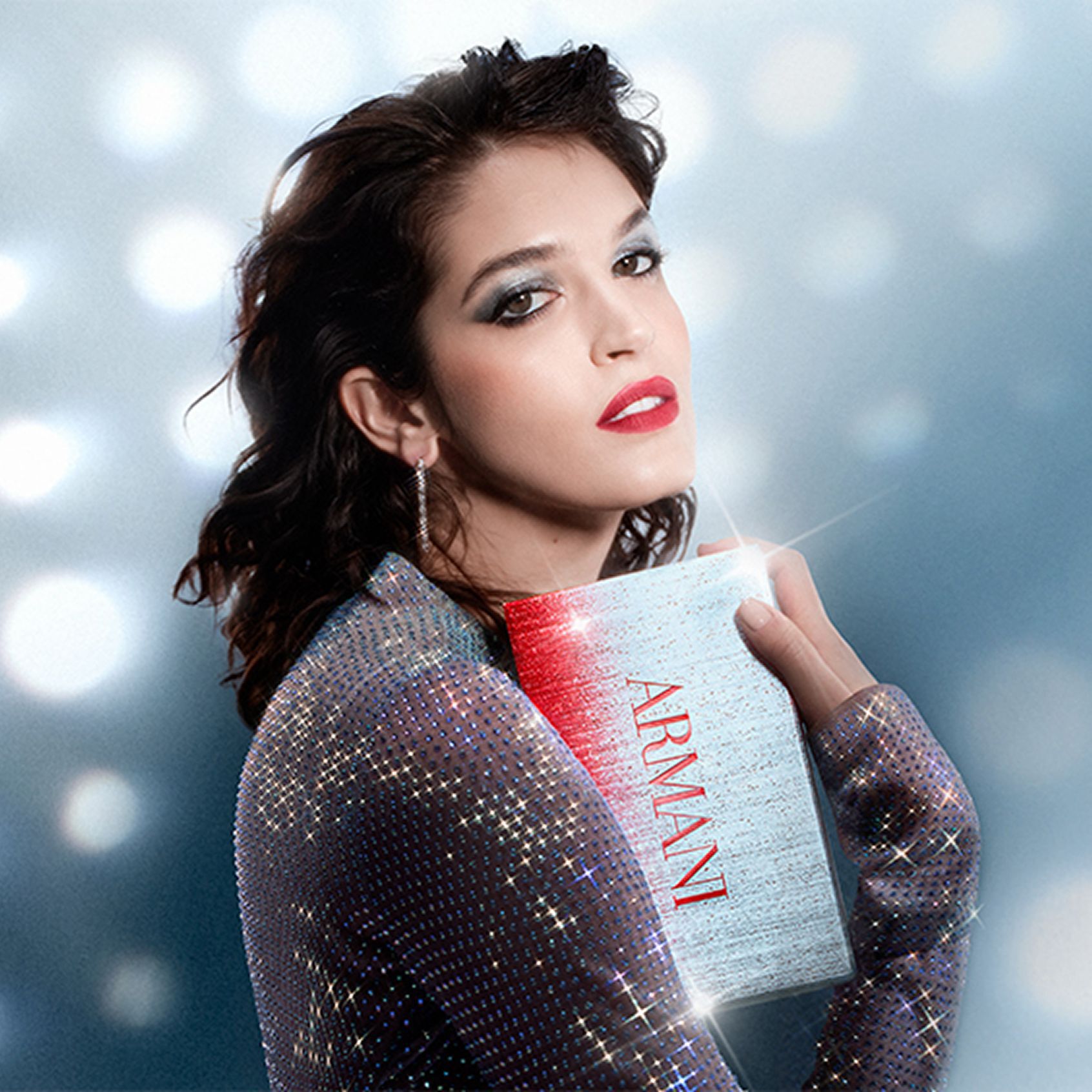 Une belle femme au maquillage a theme de Noel tient une boite cadeau de fete, sur fond de taches lumineuses reveuses de style disco.