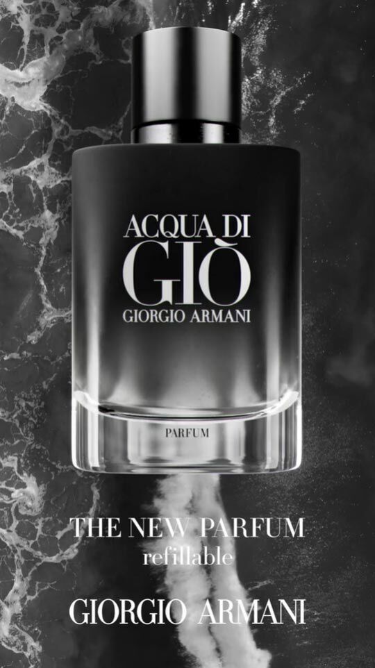 A stylish black and clear perfume bottle labeled "Acqua di Gio Giorgio Armani" surrounded by a dark, smoky background, with text indicating it's a new refillable parfum.