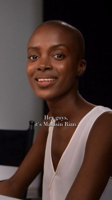 A smiling woman with a shaved head introduces herself as Madisin Rian against a simple backdrop.