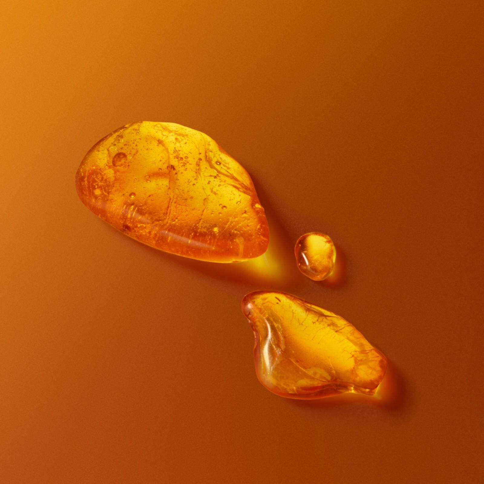 Gouden amberdruppels en harsstukjes op een warme oranje achtergrond die de geuressentie vertegenwoordigen.