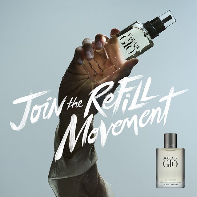 Un visuel puissant : une main tient la recharge Acqua di Gio devant le ciel avec "Join the Refill Movement" ecrit en traits de pinceau. Symbole d'un luxe durable et d'une fraicheur marine intemporelle signee Armani Beauty.