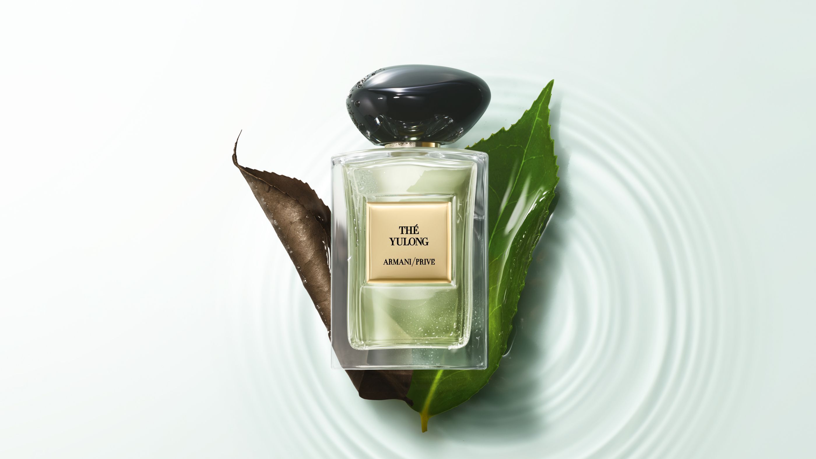 Flacon de parfum Armani/Prive « The Yulong » pose sur des feuilles au-dessus d'une eau ondulante.