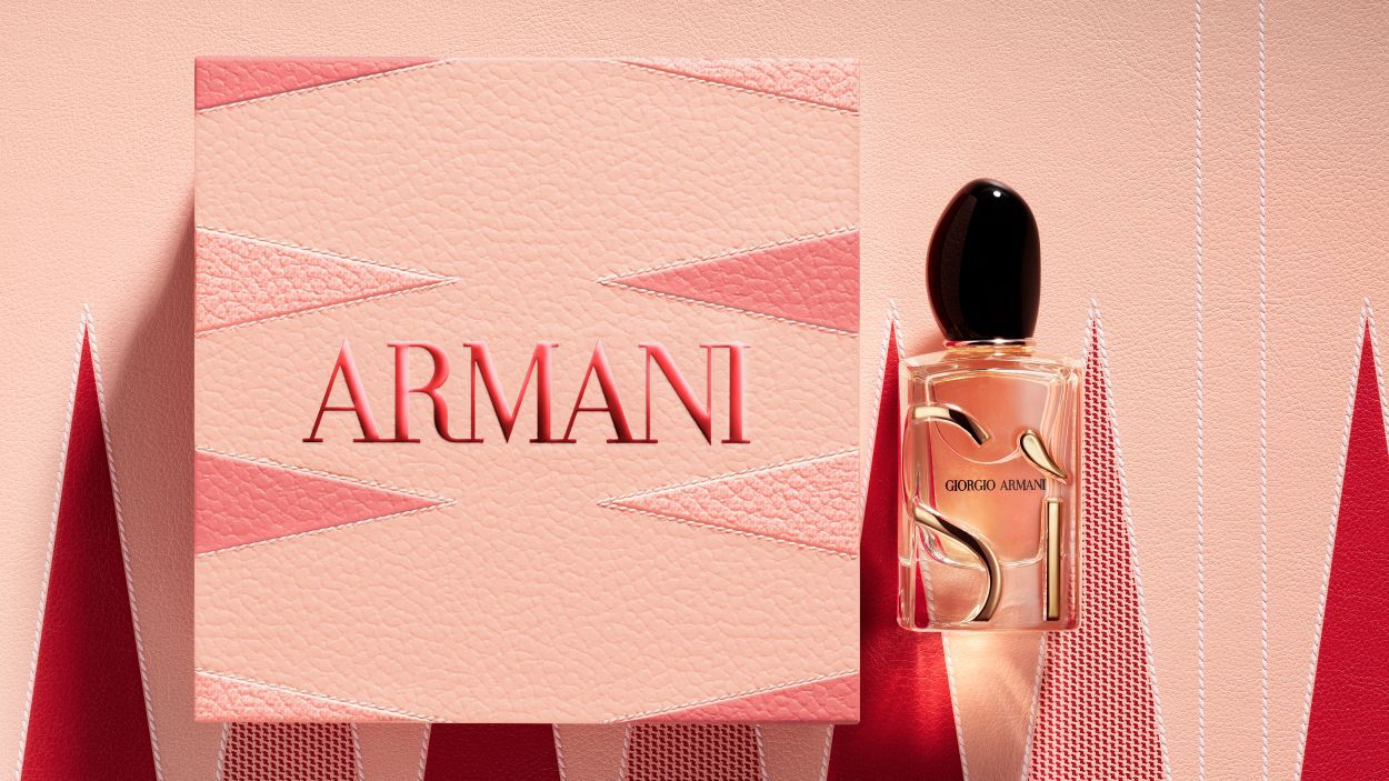 Flacon de parfum Giorgio Armani « Si » a cote d'un grand coffret cadeau Armani rose texture.