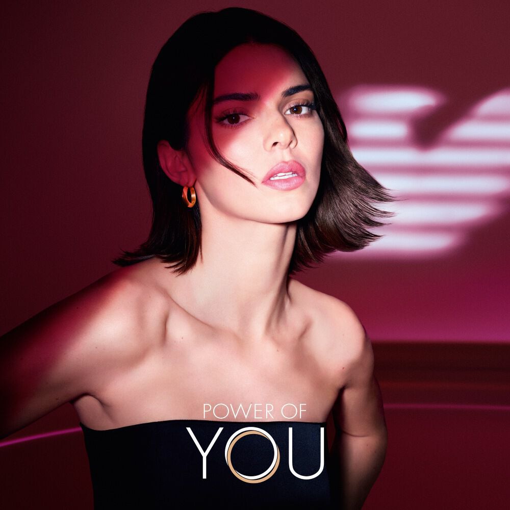 Kendall Jenner met verlichte robijnrode lichtvleugels, die vrouwelijke kracht en straling symboliseren.