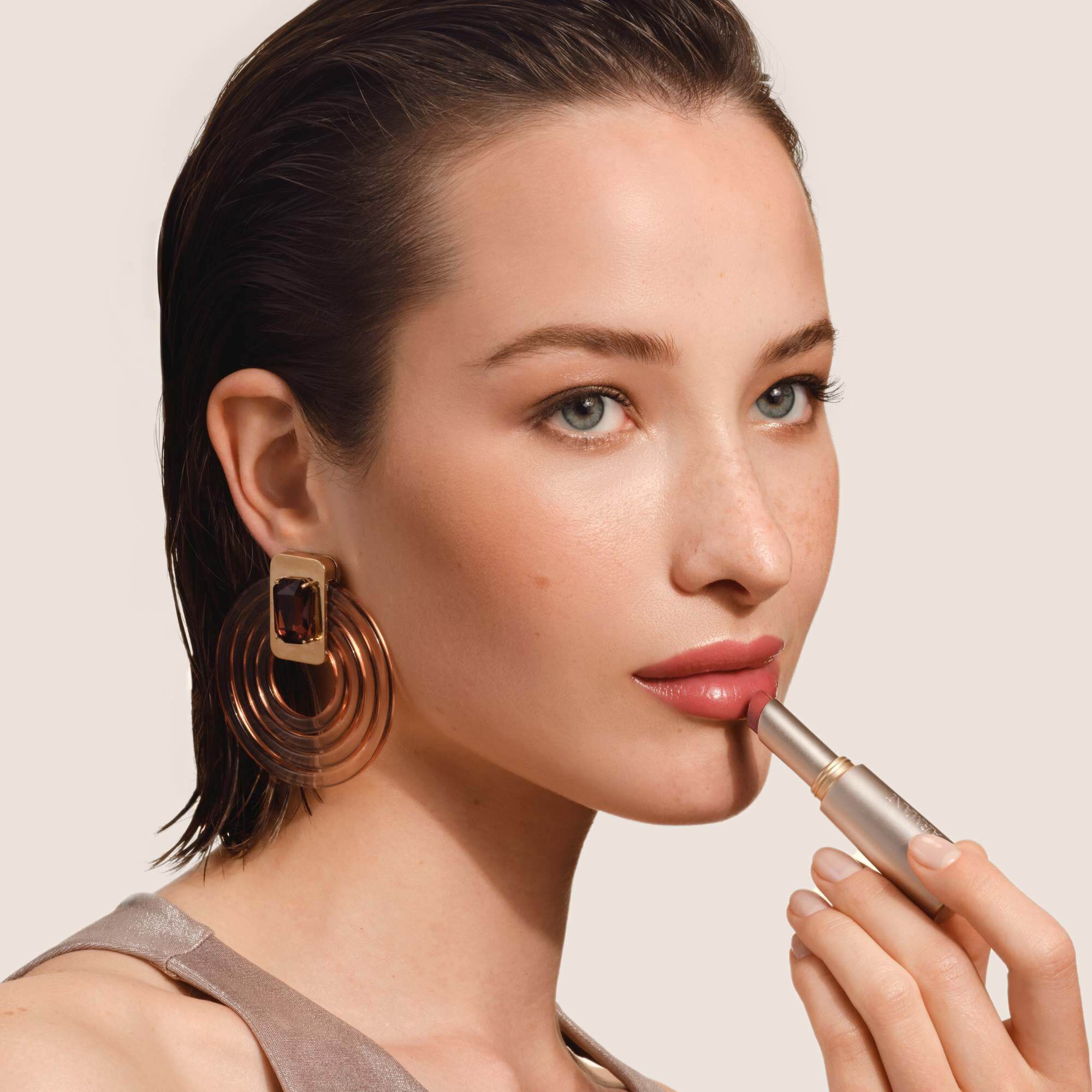 Armani Prisma Flash lippenstift aangebracht, met de nadruk op het strakke metallic ontwerp en de romige textuur van het product.