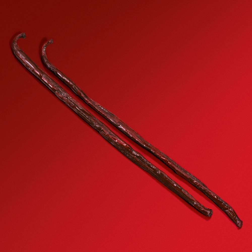 Deux bâtons en bois, texturés et de couleur brun foncé, sur un fond rouge vif.