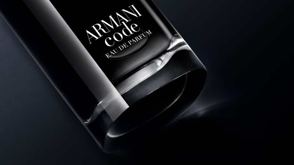 A close-up of a black glass bottle of Armani Code Eau de Parfum against a dark background, showcasing its sleek design.