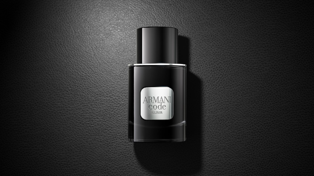 Un flacon noir du parfum Armani Code Elixir repose élégamment sur une surface noire assortie, créant un look monochrome sophistiqué