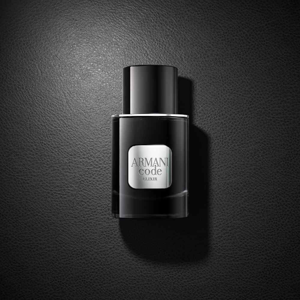 Un flacon noir du parfum Armani Code Elixir repose élégamment sur une surface noire assortie, créant un look monochrome sophistiqué